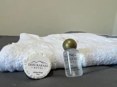a bottle of detergent and a bottle of water on a bed at Don Rafael - Hotel