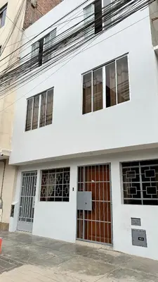 a white building with red doors and windows at WIFI Rápido A 20 min del Aeropuerto de Lima in Lima