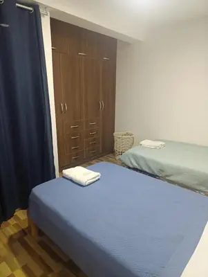 a bedroom with two beds and a closet with towels on top at Casa Hamuys - Ica in Ica