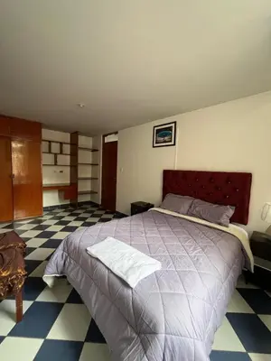 a bedroom with a large bed and a checkered floor at Allyu Wasi-Chanka in Andahuaylas