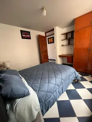 a bedroom with a blue bed and a checkered floor at Allyu Wasi-Chanka in Andahuaylas