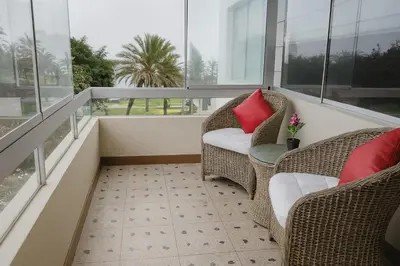 a balcony with two wicker chairs and a red pillow at Bella vista al mar y Larcomar - Miraflores in Lima
