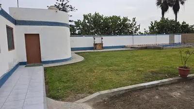 a white and blue building with a yard at Casa de campo relax y piscina in Cerro Azul