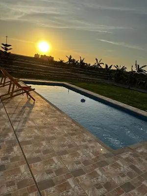 a pool with a bench and the sunset in the background at Casa de campo relax y piscina in Cerro Azul