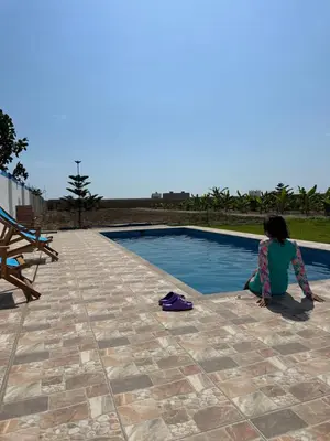 a woman sitting next to a swimming pool at Casa de campo relax y piscina in Cerro Azul