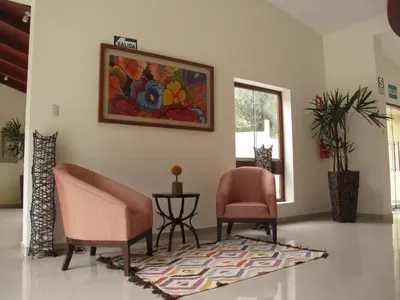 a living room with two chairs and a rug at Fundo Hotel Ayarpongo in Churín