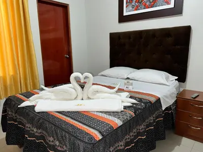 two white swans are sitting on a bed at Hotel AK7 in Nazca