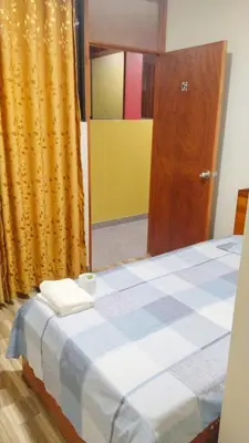 a bedroom with a bed with a blue and white checkeredkered at Hospedaje El Sureño in Satipo