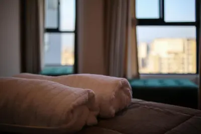 a stack of towels sitting on a bed with windows at Brand new apartment in Olivar of San Felipe in Lima