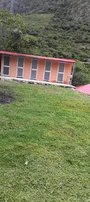 an orange building with windows in a field of grass at Chaullay Star Domes in Colcapampa