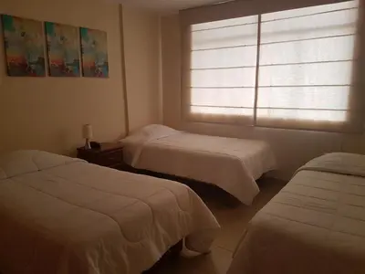 a bedroom with two beds and a window with a window shade at Belle Sand Hotel in Ica