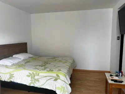 a white bedroom with a bed and a table at Amplio y acogedor departamento de 130m2 - 2do piso in Lima