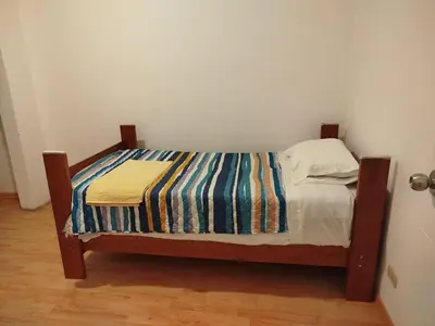 a small bed with a striped blanket on it at Amplio y acogedor departamento de 130m2 - 2do piso in Lima