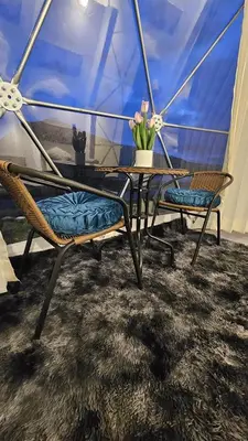 a table with two chairs and a table with flowers on it at Sky domos - laguna huaypo in Anta