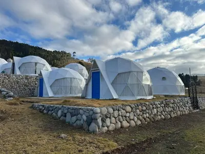 a group of domes in a field with a stone wall at Sky domos - laguna huaypo in Anta