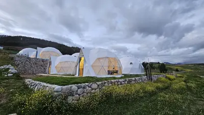 a group of domes in a field with a stone wall at Sky domos - laguna huaypo in Anta