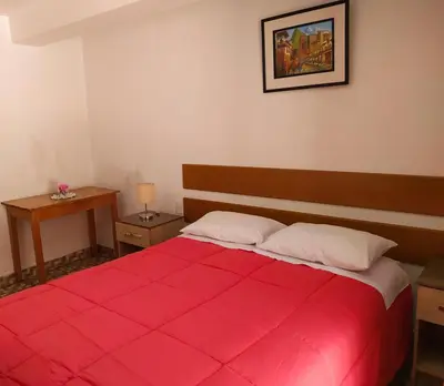 a bedroom with a large red bed with two pillows at Tambo de Ollantay Hotel in Ollantaytambo