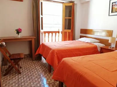 a room with two beds and a desk and a window at Tambo de Ollantay Hotel in Ollantaytambo