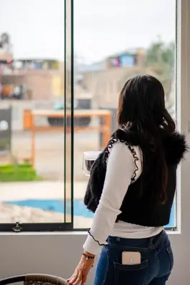 a woman is looking out of a window at Huaral House in Huaral