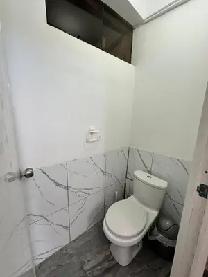 a bathroom with a white toilet and marble walls at Habitaciones para Turistas en Zona Tranquila de Cusco in Cusco