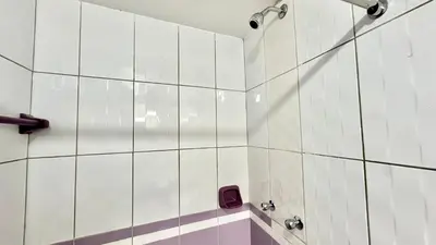 a bathroom with white tiled walls and a shower at Habitación tranquila a 15 min de Plaza Norte in Lima