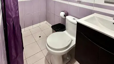 a bathroom with a white toilet and a sink at Habitación tranquila a 15 min de Plaza Norte in Lima