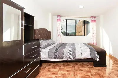 a bedroom with a bed and a dresser and a window at Alameda Suite Ayacucho in Ayacucho