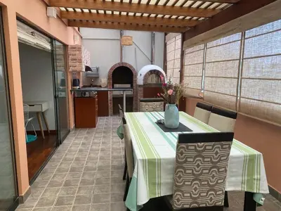 a dining room with a table and a kitchen at Departamento en Santiago de Surco in Lima