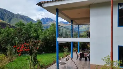 a house with a balcony with mountains in the background at Country house in nature in Sacred Valley in Huayllabamba