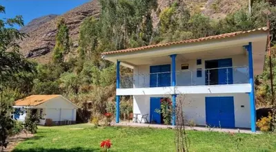a white house with blue doors in front of a mountain at Cottage in nature in Sacred Valley with mountain views in Huayllabamba