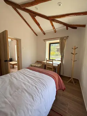 a bedroom with a bed and a table and a window at Chaqra in Urubamba
