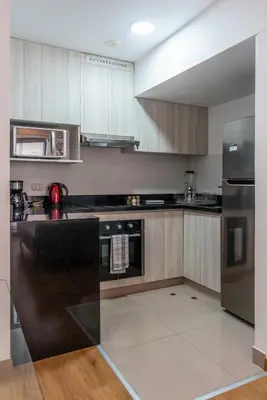 a kitchen with wooden cabinets and stainless steel appliances at Elmora 2BR by Geko in Lima