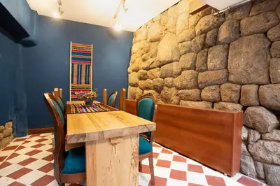 a dining room with a table and chairs and a stone wall at Casa Amará in Cusco