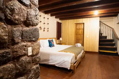 a bedroom with a bed and a stone wall at Casa Amará in Cusco