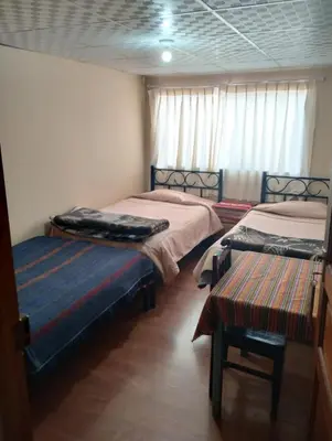 a room with two beds and a bench in it at TantaWasi in Cusco