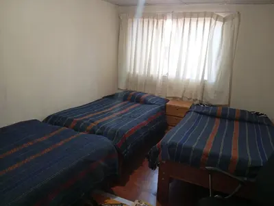 two beds in a small room with a window at TantaWasi in Cusco