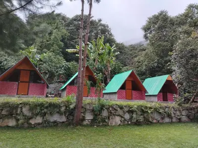 a row of red houses with green roofs behind a stone wall at Lucmabamba Cottage in Sahuayacu