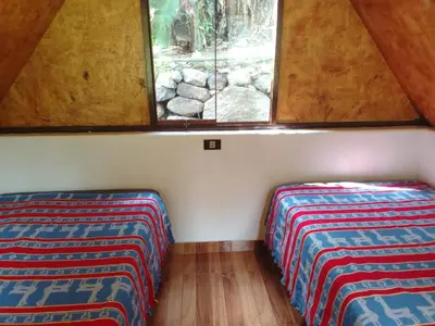 two beds in the corner of a room with a window at Lucmabamba Cottage in Sahuayacu