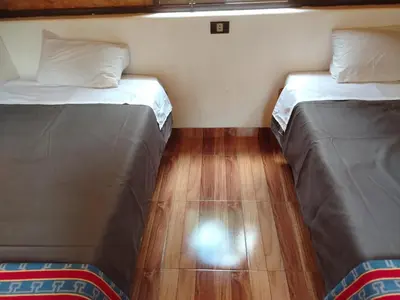 two beds in a room with a wooden floor at Lucmabamba Cottage in Sahuayacu