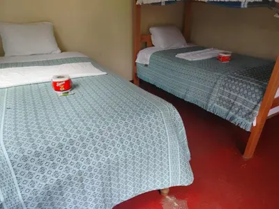two beds in a room with a cup on the floor at Lucmabamba Cottage in Sahuayacu