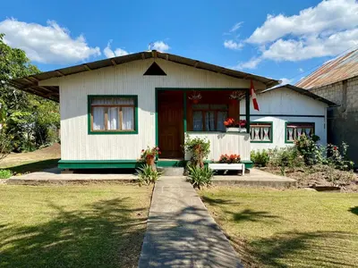 a small white house with a red door at Schütze-Haus in Oxapampa
