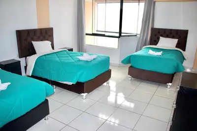 two beds in a room with green comforter at VILLA andina cusco in Cusco
