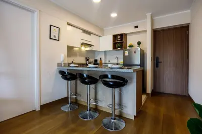 a kitchen with a bar with stools and a refrigerator at BSR Cozy Flat next to Av. Javier Prado w/ Pool&Gym in Lima