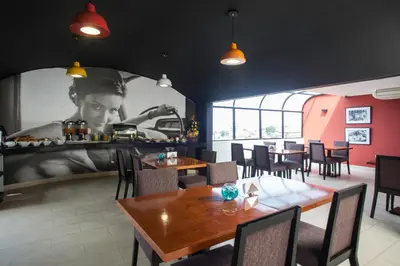 a restaurant with tables and chairs and a picture of a woman at Palmetto Hotel Business La Perla in Lima