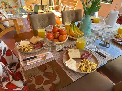 a table with plates of breakfast foods and orange juice at La posada del Minero - Oxapampa in Oxapampa