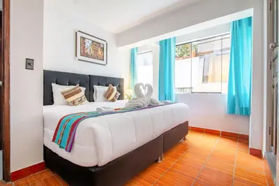 a bedroom with a large bed with blue curtains at Inkary Hotel Machupicchu in Machu Picchu