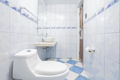 a white bathroom with a toilet and a sink at Inkary Hotel Machupicchu in Machu Picchu