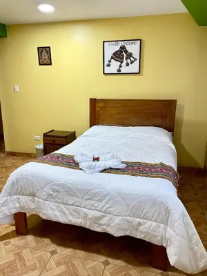 a bedroom with a large bed with white sheets at TORIBIANS Hotel in Chinchero