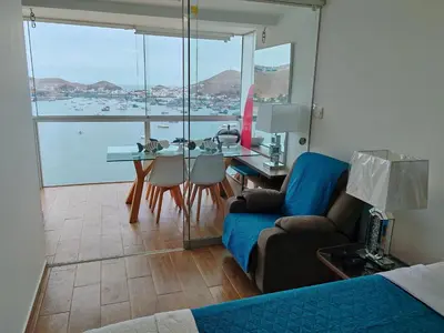 a living room with a couch and a table with a view at Confortable con vista al mar de Naplo, Pucusana in Pucusana