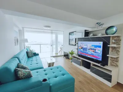a living room with a blue couch and a tv at Confortable con vista al mar de Naplo, Pucusana in Pucusana